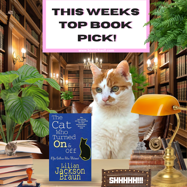 Book Reviews with Amber #348 Feline Fiction ©BionicBasil® The Cat Who Turned On & Off by Lilian Jackson Braun Amber, a regal orange-and-white cat, sits behind a desk in a grand library filled with towering wooden bookshelves and warm lighting from sconces and chandeliers. On the desk are a yellow lamp, a stack of books, a feather quill, a scroll, a small mouse figurine, and a sign that reads “SHHHHH!!!” A featured book titled The Cat Who Turned On & Off by Lilian Jackson Braun is prominently displayed, highlighting Amber’s role as a discerning feline book reviewer. At www.bionicbasil.com