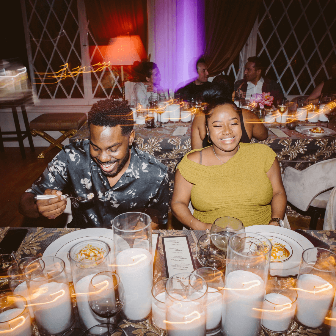 A stylish Black couple shares a joyful moment as guests at a Chef Joann event. Their laughter and energy reflect the vibrant, welcoming atmosphere of the celebration at Hollywood