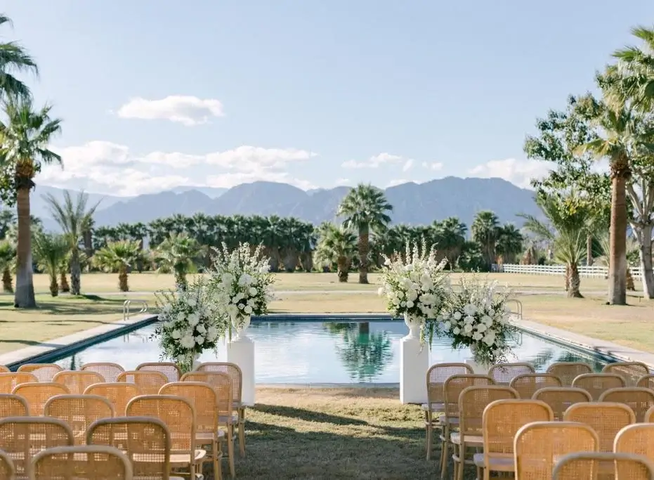 Lush poolside dining setup at The Emerson Estate in Indio, California, featuring elegant long tables, palm-lined views, and upscale catering by Chef Joann for a luxury desert event experience.