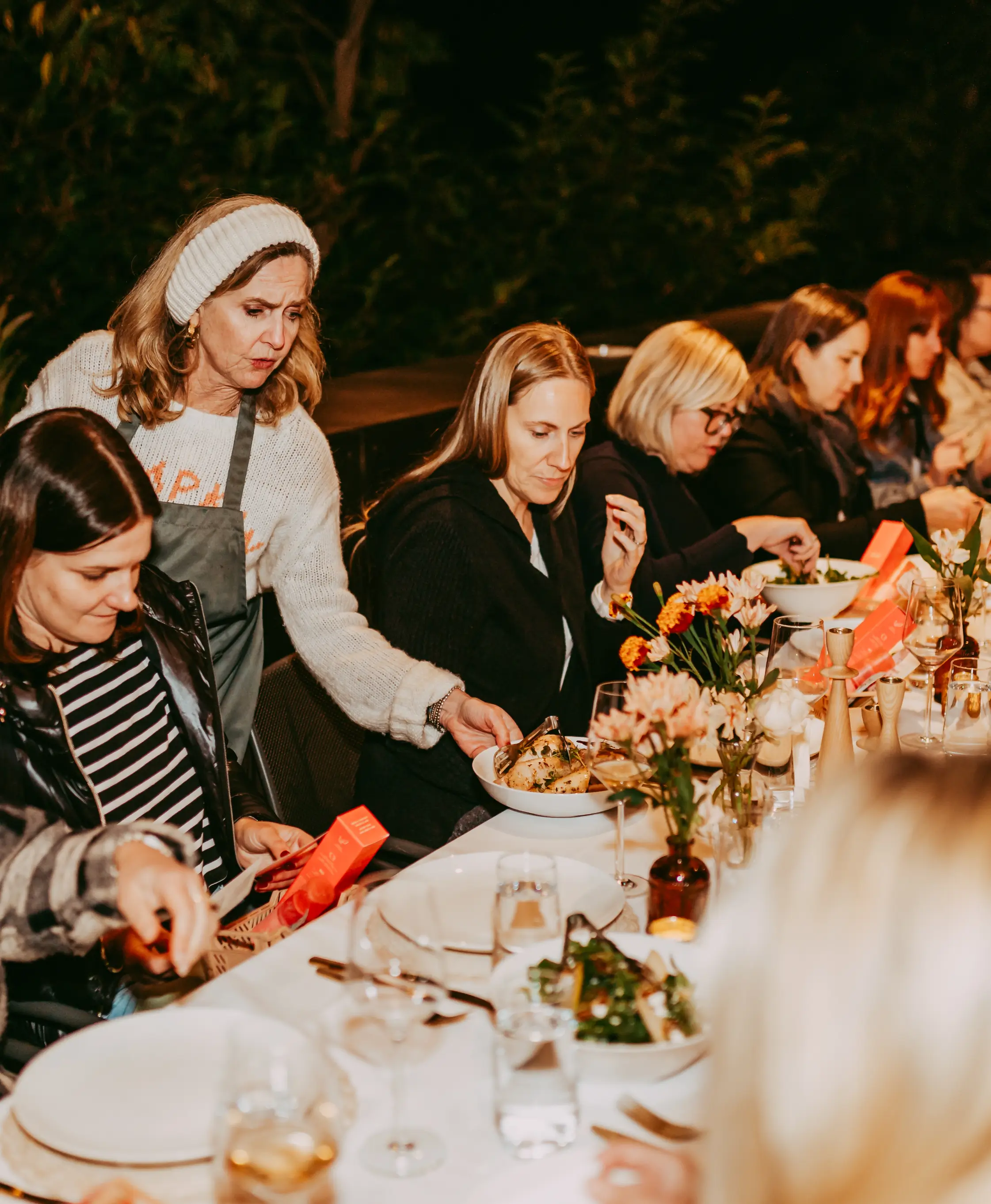 Guests enjoying Chef Joann Catering's gourmet dishes under twinkling string lights at a Palm Springs desert soirée, with warm evening ambiance.