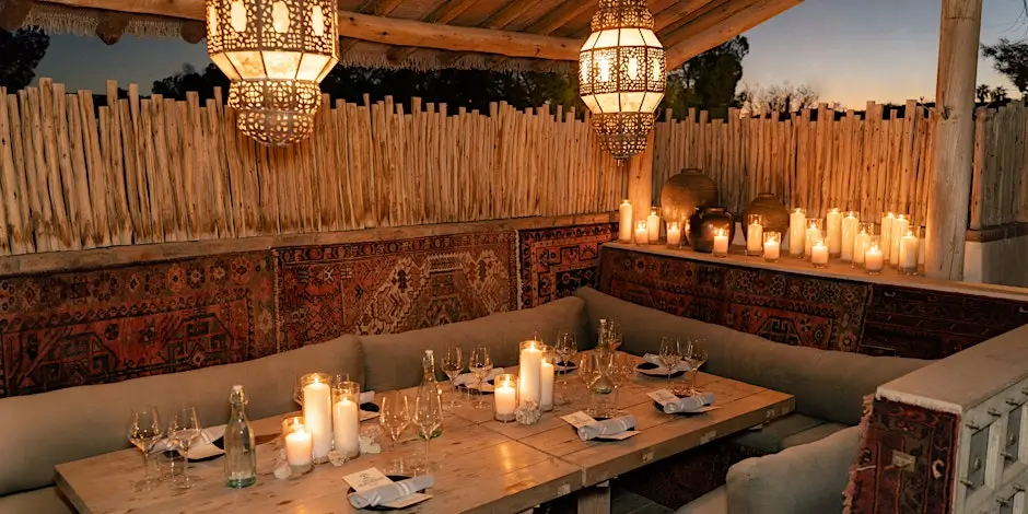 An intimate, candlelit outdoor dining setup at sunset in Southern California, styled with Moroccan-inspired décor and catered by Chef Joann.