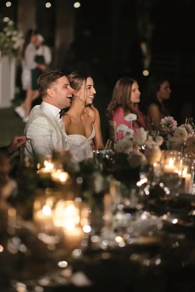 Bride and groom’s joyful cake-cutting moment amid peach blooms, at Chef Joann Catering’s dessert-focused Del Mar wedding.