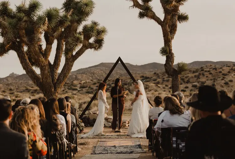 Rustic outdoor dining setup at Rim Rock Ranch in the High Desert near Joshua Tree, with string lights, communal tables, and curated catering by Chef Joann set against the rugged desert landscape.