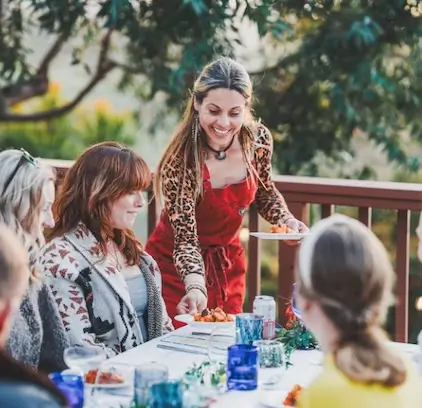 A server presents a beautifully plated dish to guests enjoying an outdoor dinner in Southern California, catered by Chef Joann.