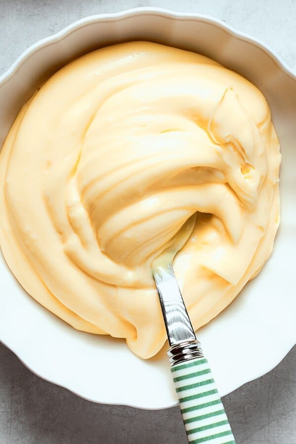 Pastry cream scooped onto a spoon, demonstrating its dense, silky consistency and structure.