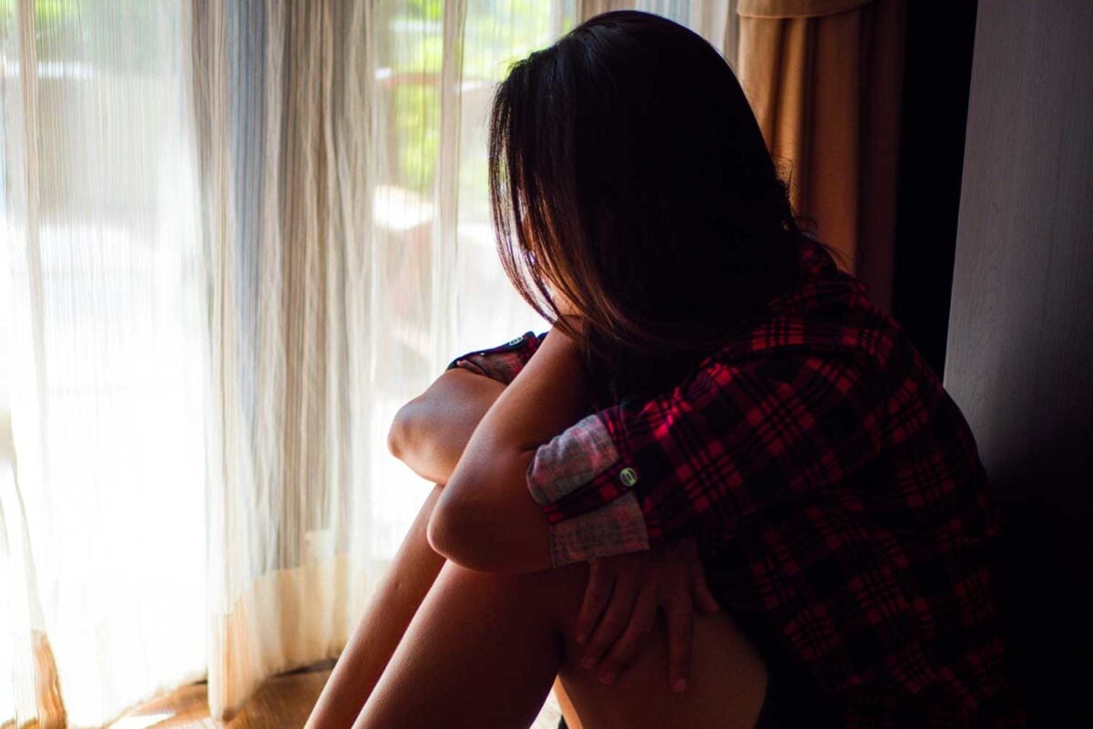 natural remedies for anxiety with woman in flannel shirt looking out a window