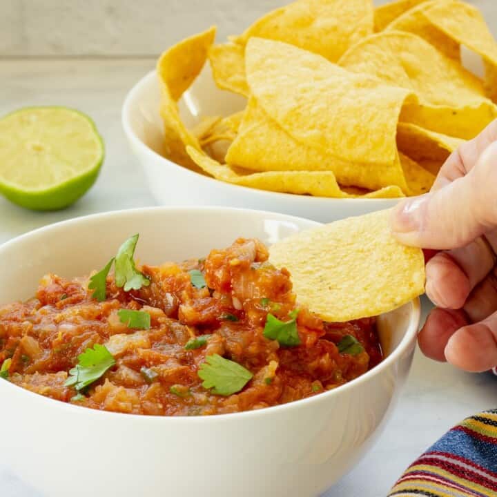 A white bowl of roasted salsa and a bowl of chips.