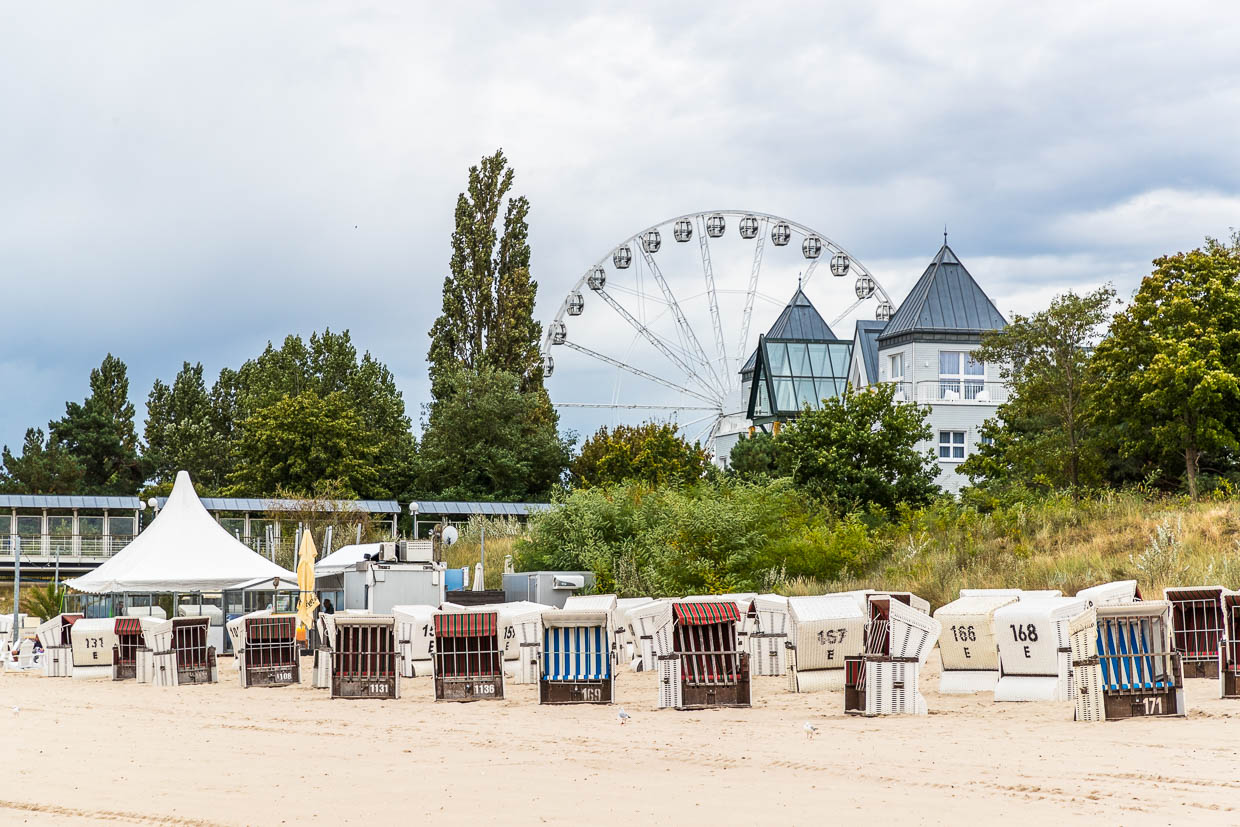 Sillas de playa en la playa de Ahlbeck con una noria al fondo. La silla de playa fue inventada por el cestero Bartelsmann en Rostock, a orillas del Báltico, en 1882. Fue hecha a medida para una anciana de la nobleza para la playa de Warnemünde y se convirtió en un popular mueble de alquiler. Elisabeth Bartelsmann, esposa del cestero, se dio cuenta de que este mueble local y estacional era más fácil de alquilar que de vender / © Foto: Georg Berg