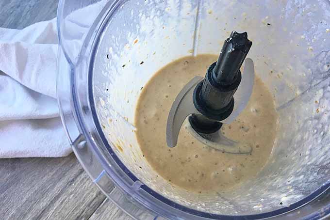 Horizontal image of a blender filled with a smoothie mixture on top of a white napkin.