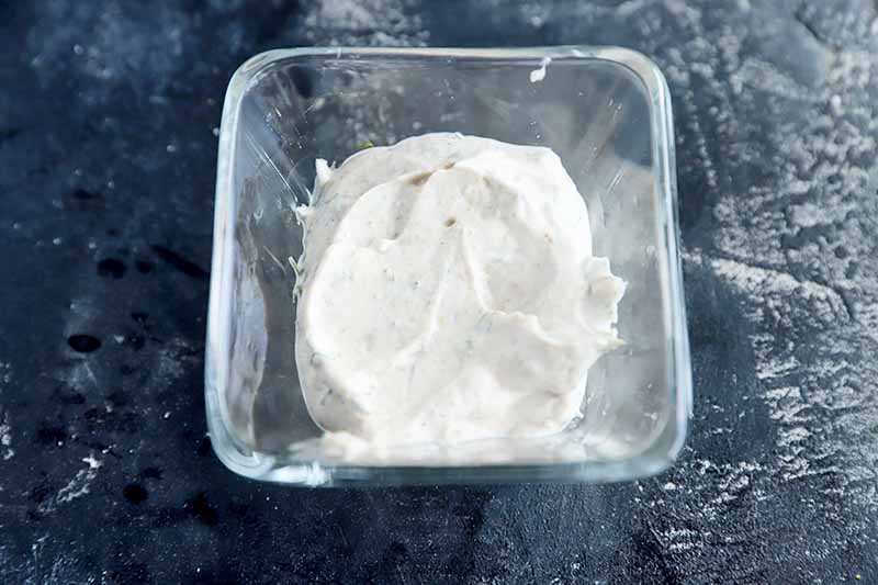 Horizontal image of a seasoned yogurt in a small glass bowl.