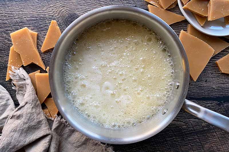 Horizontal image of a light tan boiling sugar mixture in a pot.