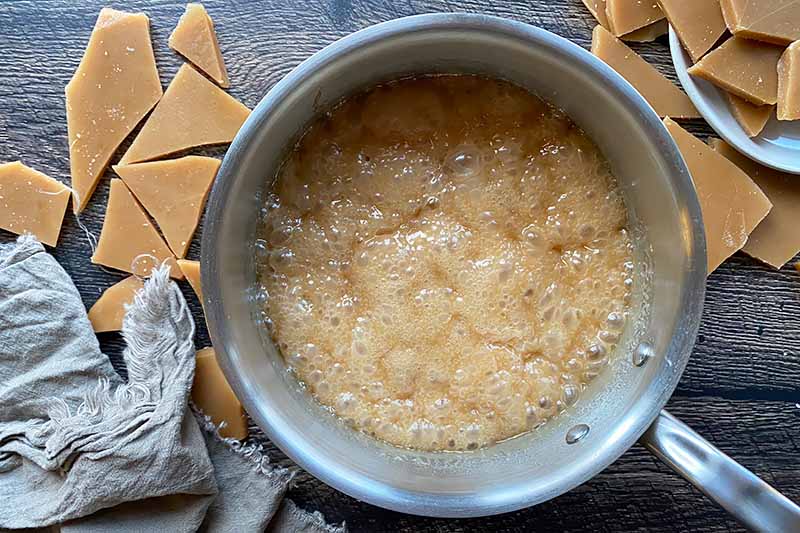 Horizontal image of a dark brown boiling mixture in a pot.