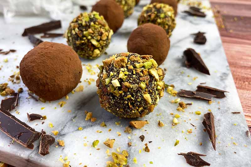 Horizontal image of two rows of candies with different coatings on a marble slab.