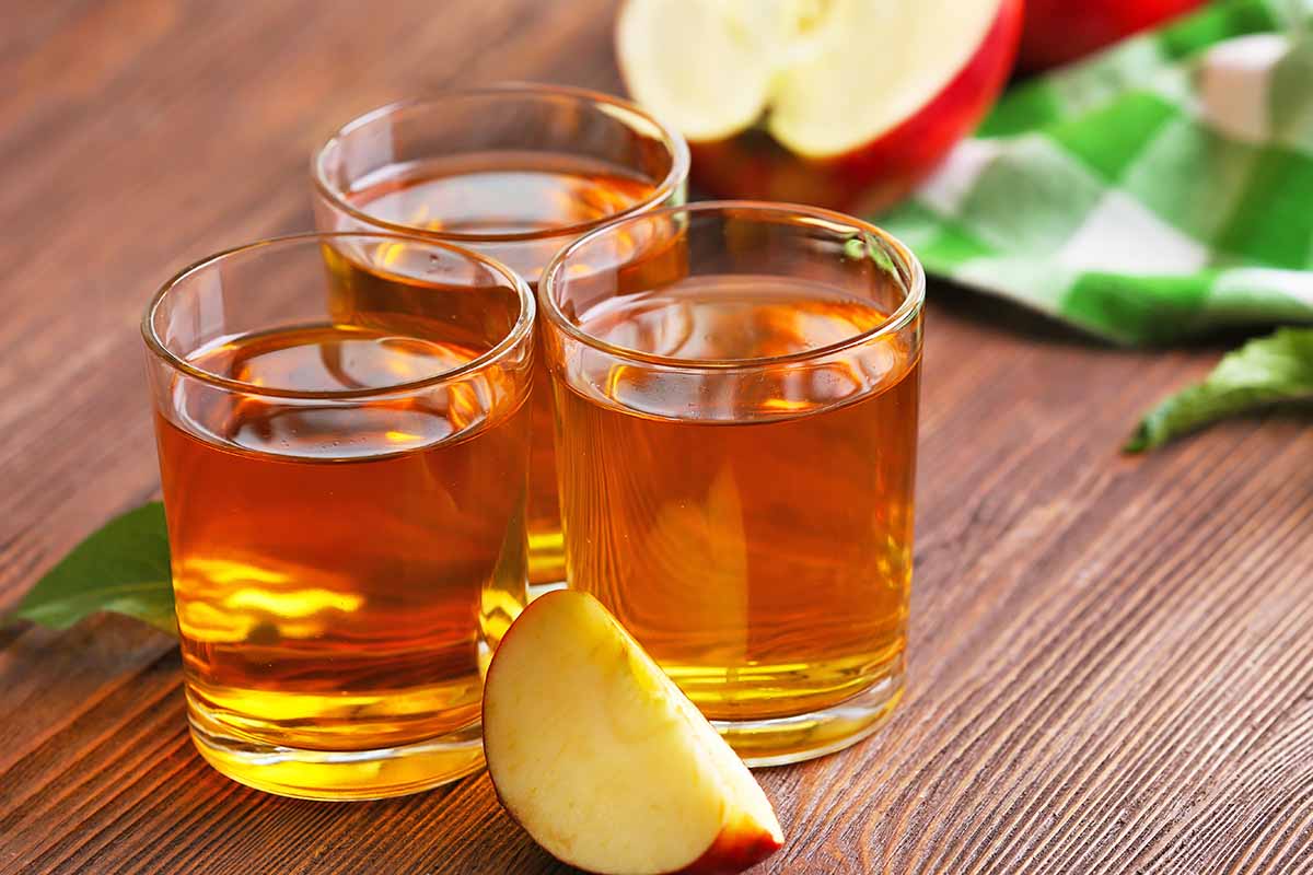 Horizontal image of three glasses filled with a juice on a wooden table.