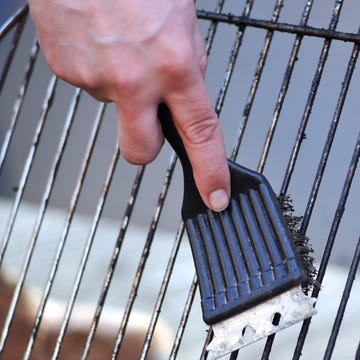 cleaning the grill with scrubber - Grillbürste human hand is cleaning the grill rost with scrubber