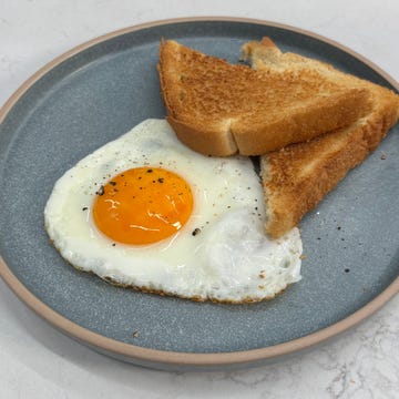 Fried egg with a sunny side up yolk and two slices of toast on a gray plate. Fried egg with a sunny side up yolk and two slices of toast on a gray plate.