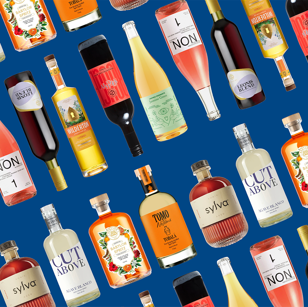 Best Non-Alcoholic Spirits, Wine, & More, According to Experts arranged assortment of various non alcoholic beverage bottles against a blue background