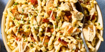 Plate of pasta topped with chicken, bacon, and drizzled sauce.