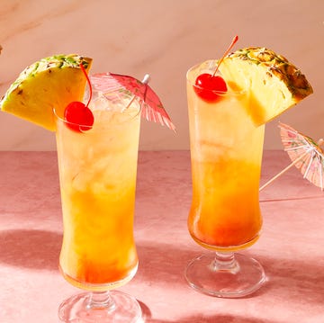 Bahama Mama orange cocktail in a glass with ice with cherries and a pineapple wedge