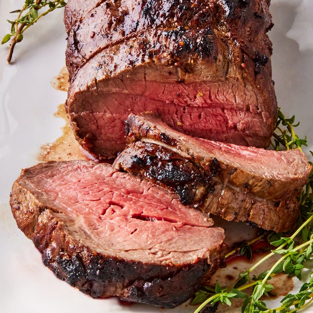 Beef Tenderloin beef tenderloin sliced on a white platter served with rosemary