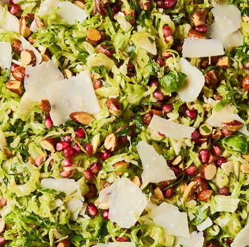 Brussels Sprouts Salad shaved brussels sprouts with pomegranates, shaved parmesan, and chopped toasted almonds in a white bowl