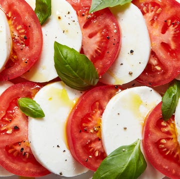 Caprese Salad sliced tomatoes, mozzarella, and basil on a plate drizzled with olive oil