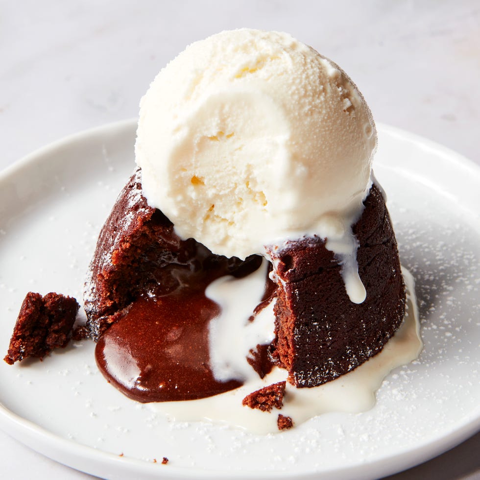 chocolate cake topped with powdered sugar sliced into with chocolate fudge spilling out