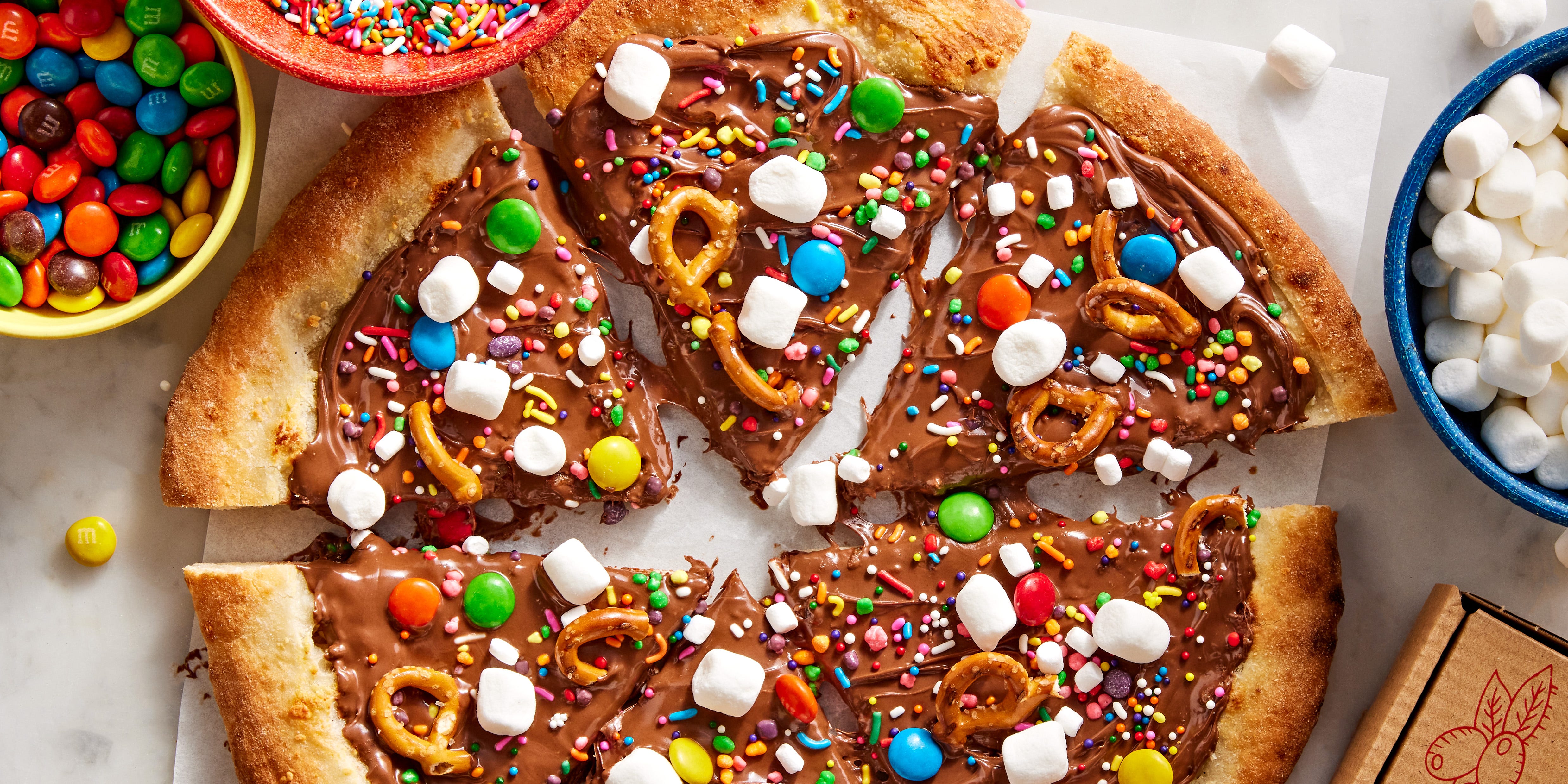 chocolate covered pizza dough topped with marshmallows, pretzels, and candy