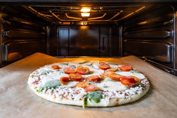 Frozen pizza mozarella on the baking sheet of an oven Frozen pizza mozarella on the baking sheet of an oven