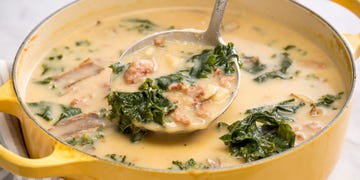 spoon serving copycat olive garden zuppa toscana from a yellow pot