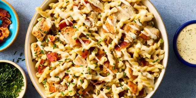 Pasta dish with chicken and toppings served alongside sauces.