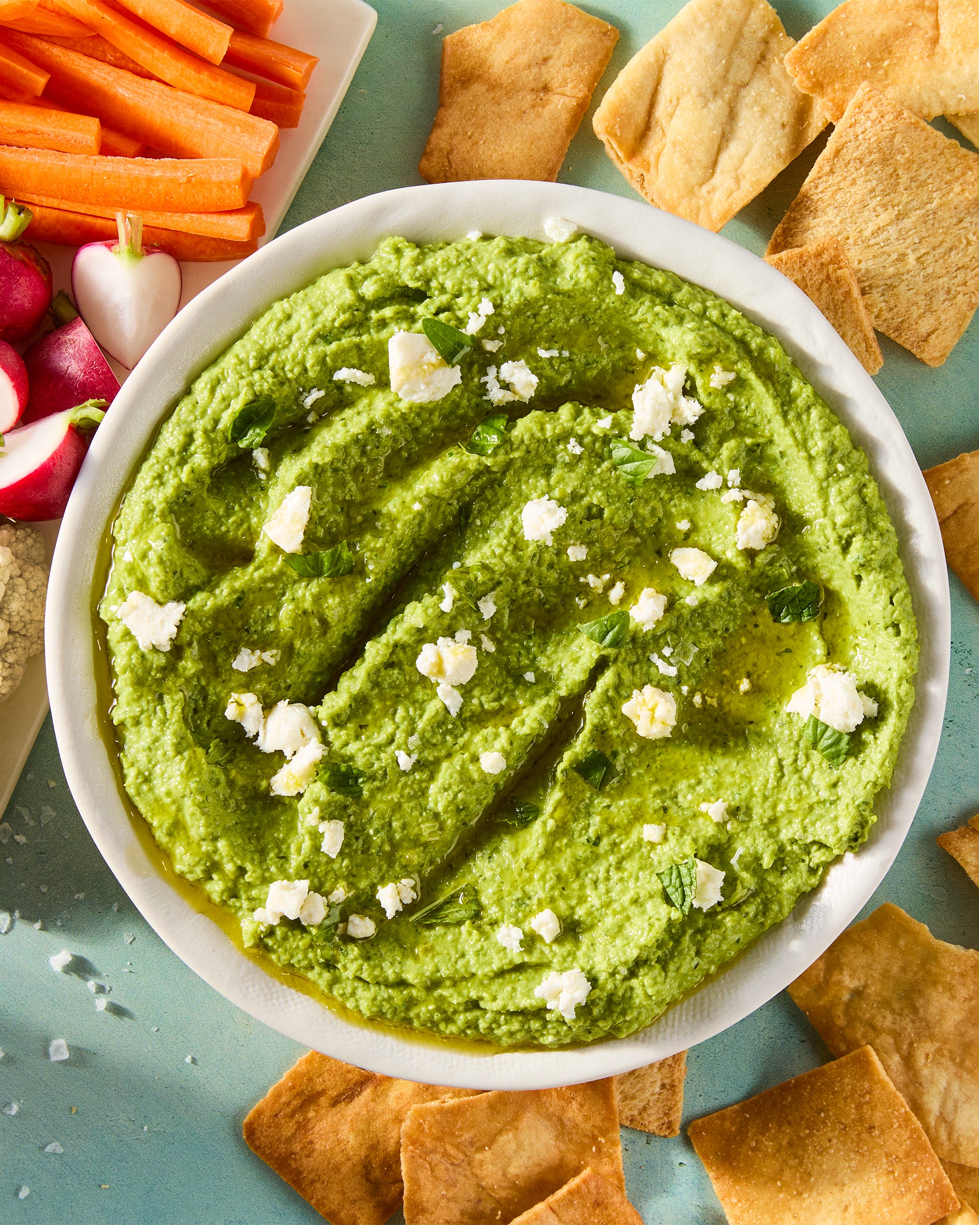 sweet spring peas are blanched until tender yet vibrant green, then blended with tangy feta cheese, basil, mint, and lemon for a luscious dip that's both creamy and savory