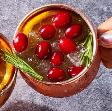 Yule Mule cranberry orange mule served in copper mugs and garnished with fresh cranberries, orange slices, and rosemary sprigs