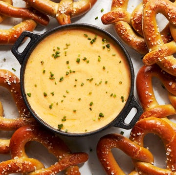 Beer cheese beer cheese in a black pot topped with chives, surrounded with soft pretzels