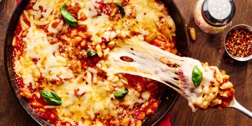 pizza beans skillet topped with mozzarella and parmesan and basil with a scoop lifting out