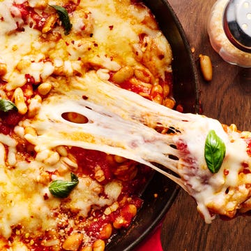 Pizza beans skillet pizza beans skillet topped with mozzarella and parmesan and basil with a scoop lifting out