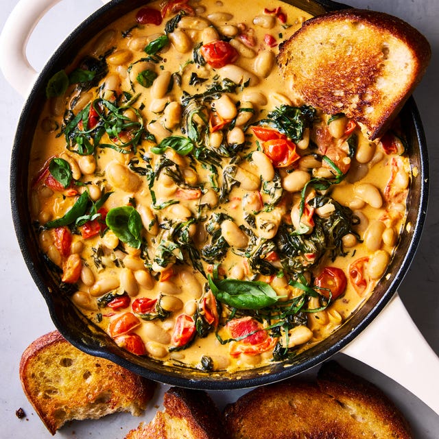 Creamy Tuscan White Bean Skillet cast iron skillet filled with creamy tuscan white beans topped with basil, with toast alongside