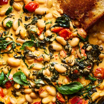 Creamy tuscan white bean skillet cast iron skillet filled with creamy tuscan white beans topped with basil, with toast alongside