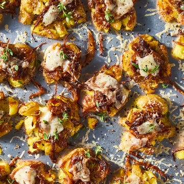 French onion smashed potatoes french onion smashed potatoes topped with caramelized onions, gruyere, and thyme on a baking sheet