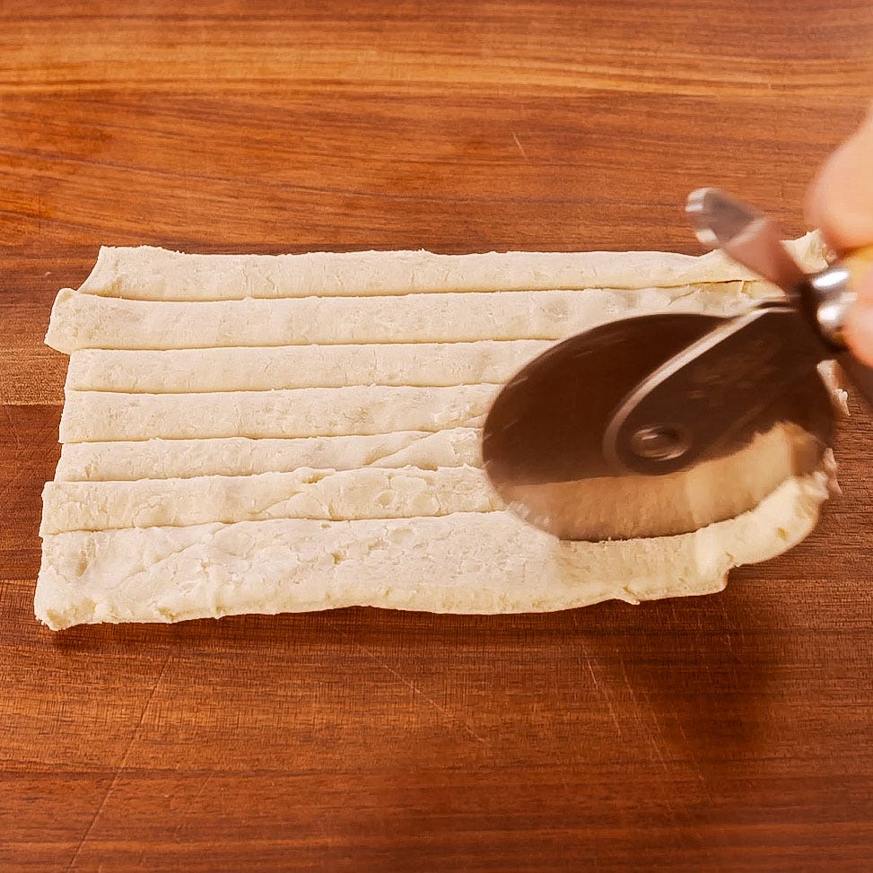 cutting dough into strips using a pizza cutter