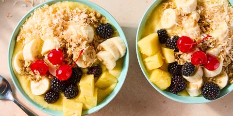 pineapple dole whip smoothie bowl in a blue bowl topped with pineapple, banana, blackberries, cherries, and toasted coconut flakes