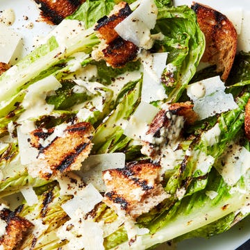 Grilled Romaine Wedge grilled romaine lettuce wedge topped with caesar dressing and croutons on a white platter