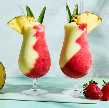 Miami Vice Cocktail pina colada and strawberry daiquiri divided in glass topped with pineapple wedge and leaves