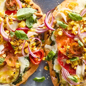 Pesto Corn Flatbread flatbread topped with pesto, corn, sliced onions, cheese, and tomatoes