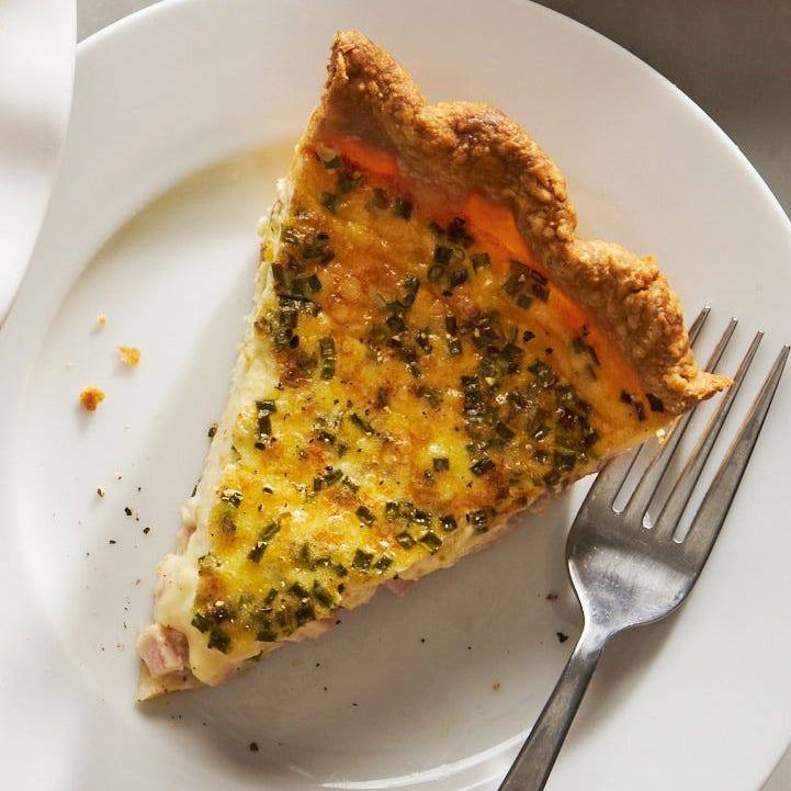 slice of quiche on a plate with a fork beside it