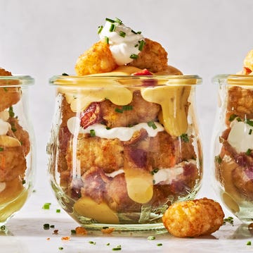 Tailgate Tots tater tots in a mason jar layered with sour cream, cheese, bacon, and chives