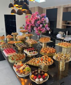 a table filled with lots of food on top of a black counter topped with flowers