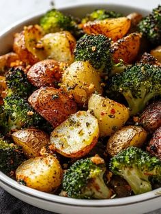 a bowl filled with potatoes and broccoli on top of a table next to a napkin