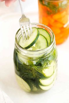 cucumber and dill pickles in a mason jar with a fork stuck into it