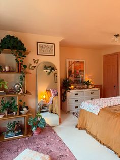 a bedroom with a bed, dresser and plants on the shelves in it's corner